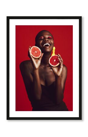 Smiling african female model holding grapefruit