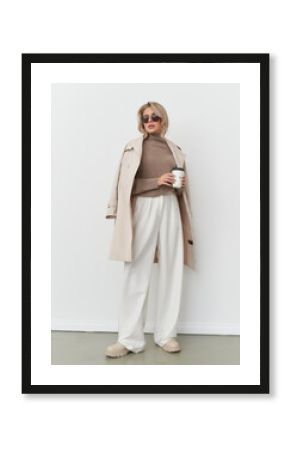 Elegant woman poses in contemporary fashion with coffee in stylish studio setting