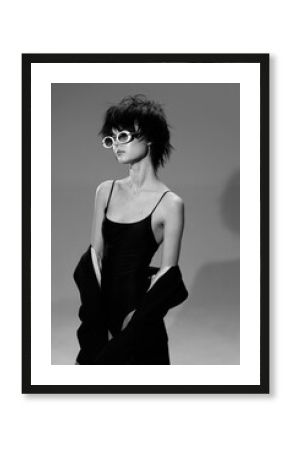 Black and white stylish woman wearing sunglasses with short hair and a confident pose in a minimalistic setting.