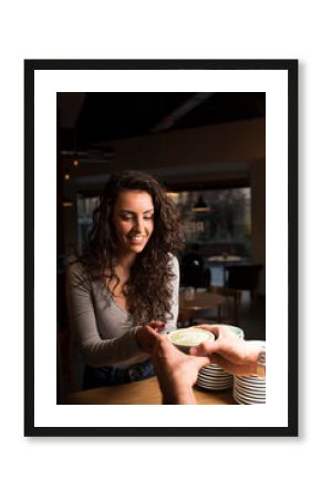 Smiling woman taking coffee cup at cafe