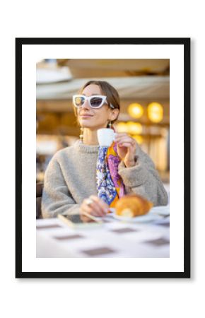 Woman having breakfast with croissant and coffee at traditional italian cafe outdoor. Woman wearing sunglasses and shawl in hair. Concept of italian lifestyle and travel