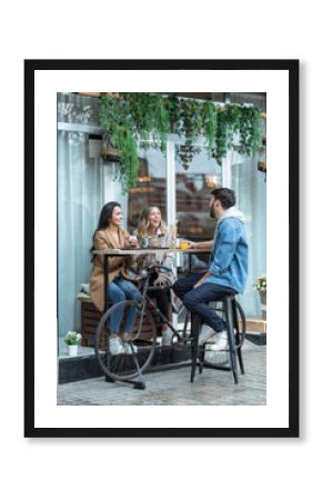 Group of cool friends sharing a brunch together while talking and looking the smartphone on the healthy coffee shop terrace.