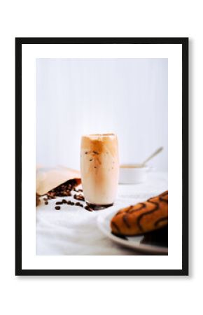 Vaso de Café Dalgona, Delicioso café coreano, café frío, con fondo blanco, rodeado de granos de café y bollos dulces de chocolate