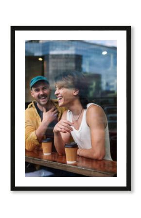 Happy gay men with coffee cups seen through window of cafe