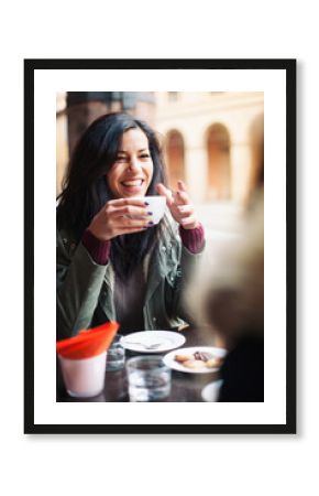 Young woman drinking coffee in a cafe outdoors. 