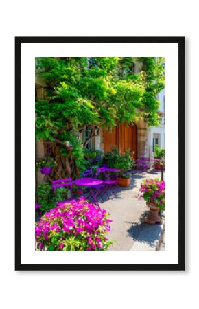 Cozy street with flowers and tables of cafe  in Paris, France