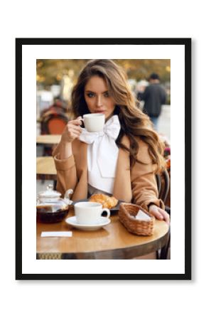 beautiful woman with dark hair in elegant outfit sitting in cafe