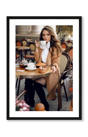 beautiful woman with dark hair in elegant outfit sitting in cafe