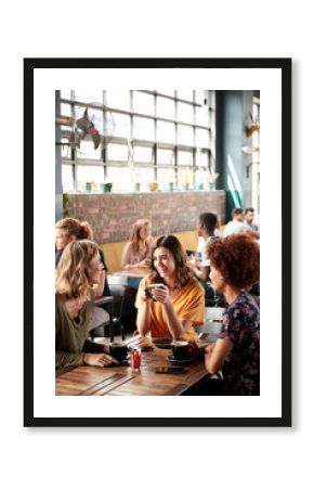 Three Young Female Friends Meeting Sit At Table In Coffee Shop And Talk