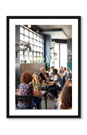 Interior Of Busy Coffee Shop With Customers Sitting At Tables
