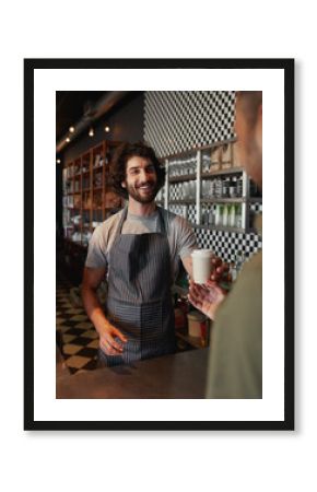 Smiling mature waiter giving take away coffee to man at cafeteria