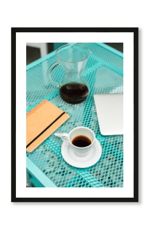 Notepad, laptop, coffee cup and pot kept on table at cafe