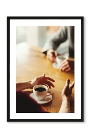 Hands of two unrecognizable businessmen having business talk over coffee sitting at table in cafe