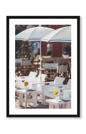 Relaxing in sunlit lounge chairs adorned with cheerful sunflowers at a vibrant outdoor café during a warm summer afternoon