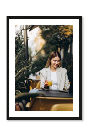 Young business woman sitting in a cafe drinking juice and working on a computer