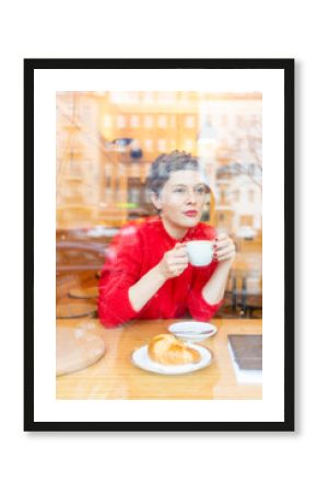 Mid adult woman in cafe drinking coffee looking out, window view