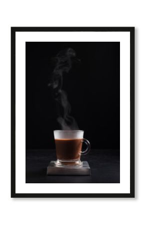 Café caliente y humeante en taza de vidrio sobre fondo negro. Aislado