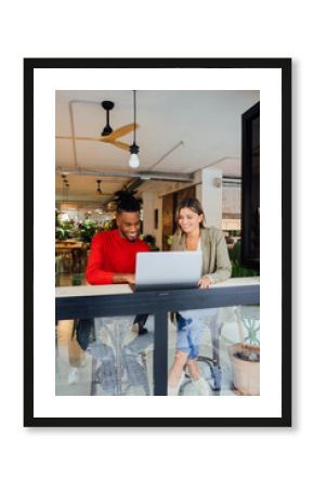 Smiling business colleagues working on laptop at cafe