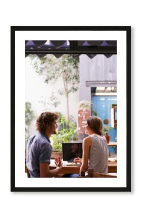 Students, friends and laptop in coffee shop with notes for studying, break and relaxation. Young people, mates and happy together with smile and tech for internet and research at cafe in Amsterdam
