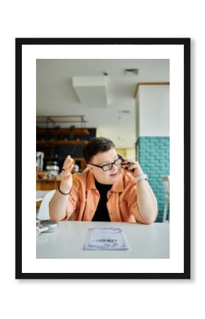 A man with Down syndrome makes a phone call while looking at a menu at a cafe.
