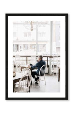 Mature man with digital tablet drinking coffee in cafe
