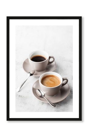 Two white cups of hot black coffee with milk isolated on bright marble background. Overhead view, copy space. Advertising for cafe menu. Coffee shop menu. Vertical photo.