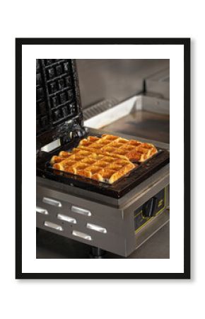 Cooking belgian waffles in the waffle iron in cafe kitchen