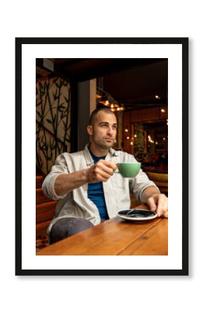 Thoughtful man savoring a warm cup of coffee in a stylish cafe, enjoying a peaceful moment of reflection amidst a busy day