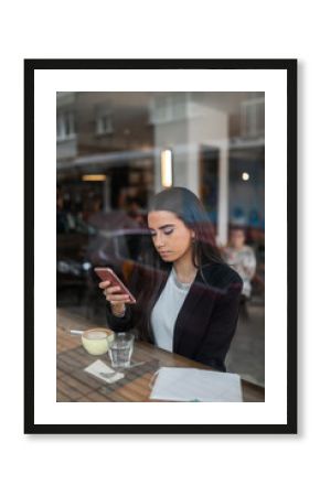 Elegant young woman checking phone at café