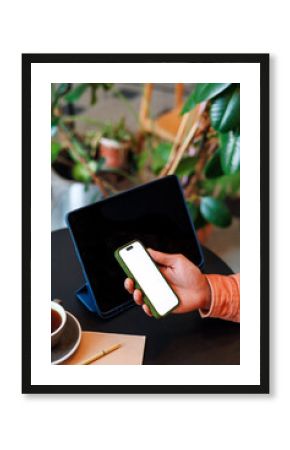 Hand Holding Smartphone with white screen by Tablet