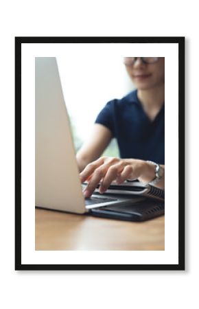 Asian business woman working with laptop computer, typing on keyboard, searching the information, remote working at cafe. Student studying online at coffee shop, vertical composition