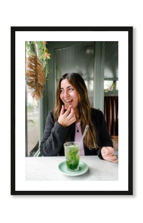 Smiling woman eating a cookie at a window table in Alkmaar café