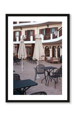 Black tables and chairs in a street cafe near a hotel