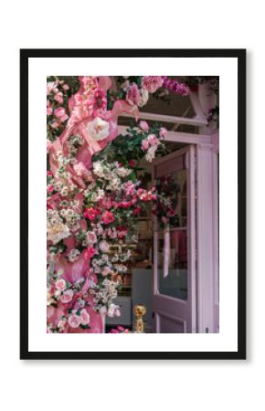 A café entrance with a pink door and pink aesthetic, adorned with pink flowers.