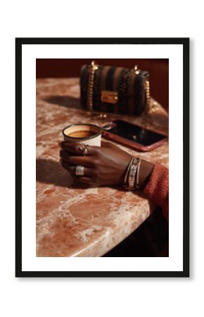 Black woman wearing luxury jewelry and holding a coffee cup