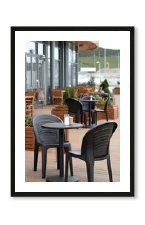 Outdoor seating area in a modern café featuring black chairs and tables with planters on a cloudy day