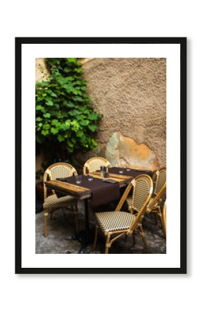 Tables with wooden chairs placed outside a restaurant on the street