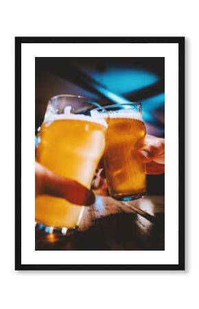 Closeup view of a two glass of beer in hand. Beer glasses clinking in bar or pub