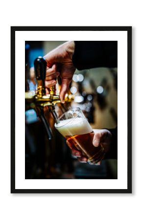 bartender hand at beer tap pouring a draught beer in glass serving in a bar or pub