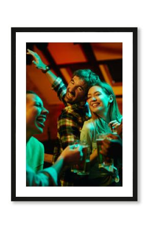 Happy couple dances with their friends during night party in pub.