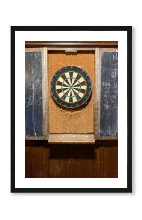 Well used dart board in a pub with chalk boards for keeping score.