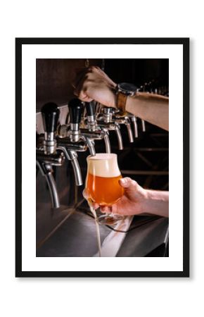 Bartender pouring fresh beer into glass in pub