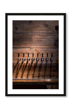 Beer tap handles against a rustic wooden wall in a pub