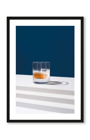 Un vaso de whisky con hielo sobre un fondo azul 