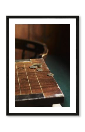 A pub games table with copper coins laid on the surface. A traditional carved chair.