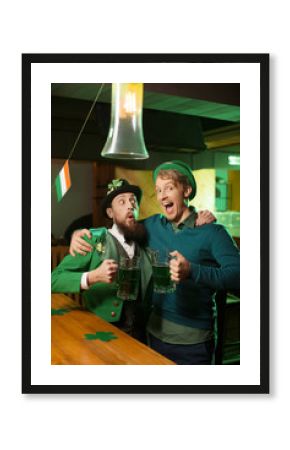 Dark-haired bearded young man in a leprechaun hat and his friend celebrating st.patricks day