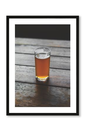 Half pint glass of craft beer on a pub bench.