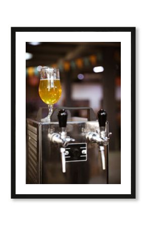 Glass of refreshing beer on cooling machine in pub