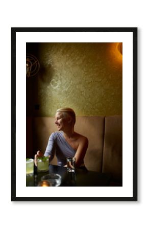 A lady smile at her friend while having a drink.