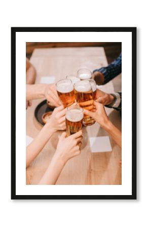 partial view of multicultural friends clinking glasses with lager beer in pub